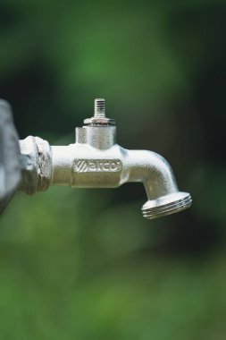Gri bahçe musluğunun kapanışı. Güzel, yeşil bir arka planda musluk yok.
