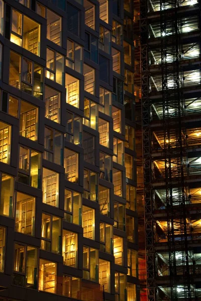 Een Verticaal Shot Van Een Kantoorgebouw Ramen Verlicht Avond — Stockfoto