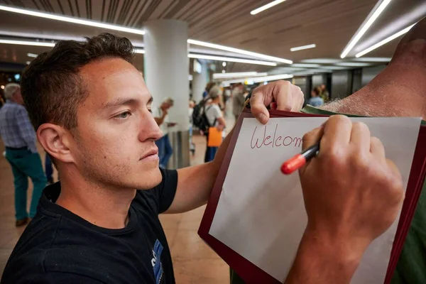Young Hispanic Man Writing Airport Welcome Greeting — Stock Photo, Image