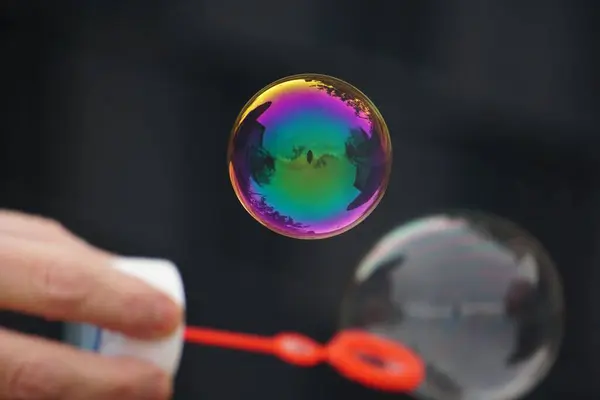 Person Som Blåser Såpbubblor Med Färgglada Reflektioner Luften — Stockfoto