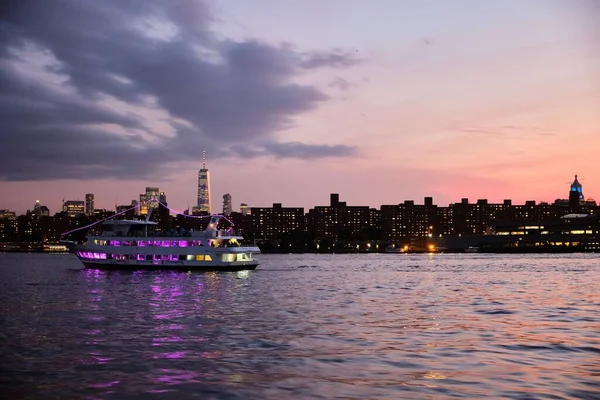 在黄昏时分 带着明亮的纽约天际线 在哈德逊河泛着紫色灯光的游轮 — 图库照片