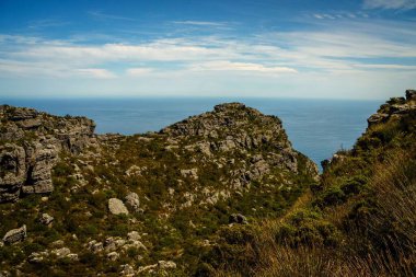 Güneşli bir günde mavi bulutlu gökyüzünün altında Masa Koyu manzaralı bir dağ.