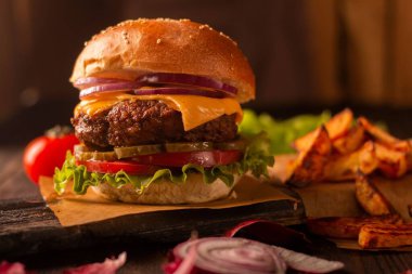 Biftek, peynir, soğan, domates ve turşu ve patates kızartmalı yeşil salata.