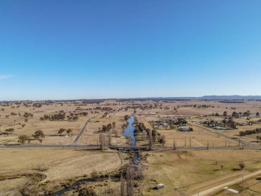 İnsansız hava aracı, gün ışığında Avustralya 'nın Deepwater şehrinde bir köprü ve dar bir nehir ile doğal manzaralara tepeden bakıyor.