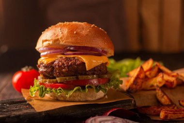 Biftek, peynir, soğan, domates ve turşu ve patates kızartmalı yeşil salata.