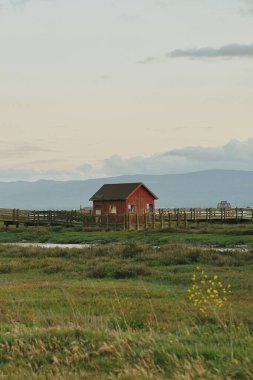 Gün batımında bulutlu gökyüzünün altında küçük bir ahır.