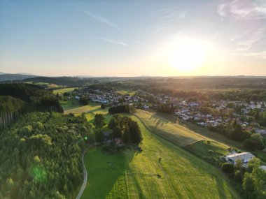 Yeşil sık ağaçlarla dolu güzel bir manzara ve temiz bir gökyüzüne karşı kırsal bir kasaba.