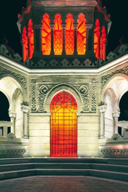 Geceleri turuncu ve kırmızı ışıklı egzotik bir binanın dikey yakın çekimi. İzmir saat kulesi