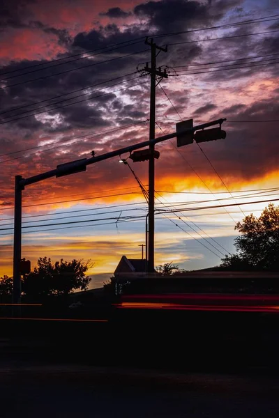 Вертикальный Снимок Красивого Заката Размытыми Автомобильными Огнями Переднем Плане — стоковое фото