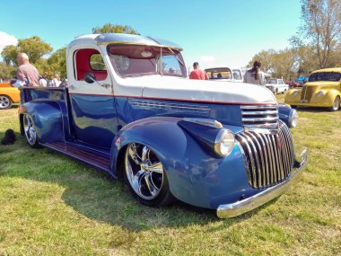Chascomus, Arjantin - 2009, 2022: 1940 model eski klasik klasik beyaz ve mavi Chevrolet Chevrolet 3100 model hot rod kamyonet. Doğa çimen ağaçları.