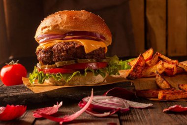 Biftek, peynir, soğan, domates ve turşu ve patates kızartmalı yeşil salata.