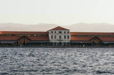 Gün batımında arka planda binayla birlikte denizin yatay görüntüsü..