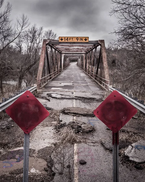 赤い看板が閉じられた橋の上の壊れた古い道路の垂直ショット — ストック写真