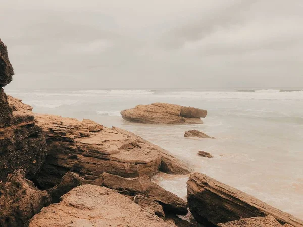 Een Zandstrand Met Rotsachtige Oppervlakken Onder Een Bewolkte Hemel — Stockfoto