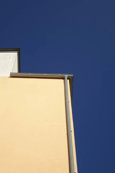 青い空に対して垂直水パイプとベージュの石造りの建物の低角度ショット — ストック写真