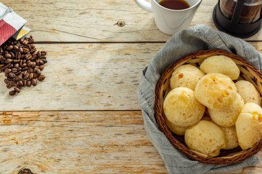 Sepet içinde peynirli ekmek veya 'pao de queijo' ve kahve makinesi ve kahve çekirdeği, masanın etrafında kumaş ve fotokopi alanı ile