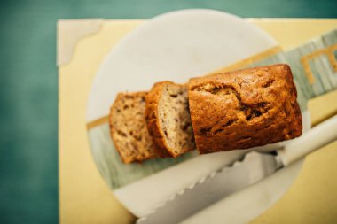 Yüksek açılı küçük muz ekmeği mermer üzerinde, pirinçten altın ve tırtıklı bıçak.