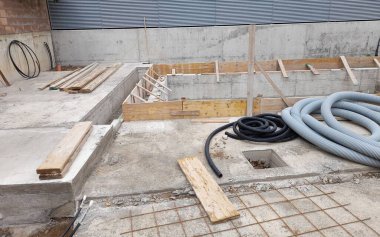 Ahşap malzemeler, borular ve beton hortumlarla dolu bir inşaat alanı.