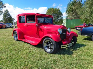 Eski kırmızı Ford Model. Özel yapım Tudor Sedan 1928 - 1931. Hot Street çubuğu. Yan görüş. Doğa yeşili çimenler ve ağaçlar. Klasik araba şovu. Kopyalama alanı
