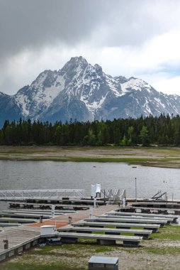 Arka planda dağları ve ormanı olan göl kıyısında bir rıhtım.