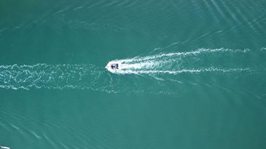 Okyanusta yüzen ve arkasında beyaz bir iz bırakan bir motorlu teknenin hava görüntüsü.