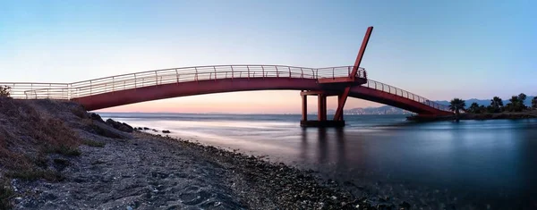 横越大海的一座红色金属桥的横向全景摄影 日落时海滨风景的长期曝光摄影 — 图库照片