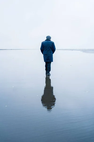 水面に映るワシントンの海辺を歩く男 — ストック写真