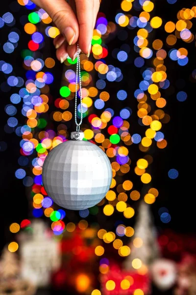 Een Menselijke Hand Houden Kerstbal Tegen Bokeh Lichten Achtergrond — Stockfoto