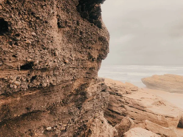 多云的天空下有岩石悬崖的沙滩 — 图库照片