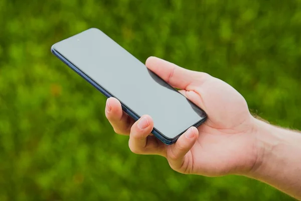 Een Zwarte Smartphone Een Mensenhand Met Wazige Kruiden Aan Horizon — Stockfoto
