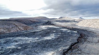 Arkasında bulutlar olan kurak ve vahşi bir manzara.