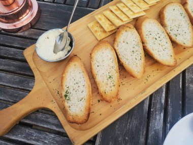 Krem peynirle kaplı bir kesme tahtası, baget ve kraker - yemek estetiği