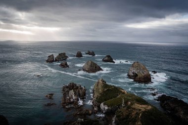 Kasvetli bir gökyüzünün altında kaya oluşumlarıyla güzel bir deniz manzarası.
