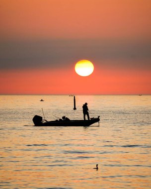 Gün batımında denizde bir balıkçı
