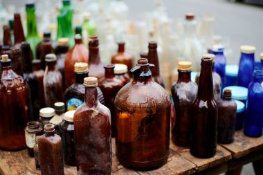 Eski ahşap bir masanın üzerindeki boş şişe yığını.