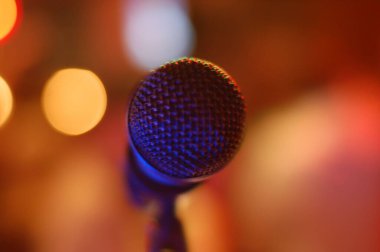 Sahnede renkli ışık saçan bir mikrofonun yakın çekim görüntüsü.