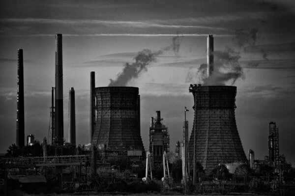 A grayscale shot of an industrial factory with towers of smoke in Germany