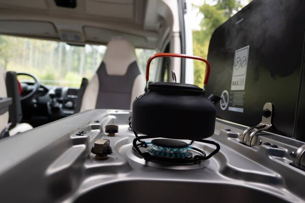 A closeup shot of a black kettle on the gas in a campervan in Germany