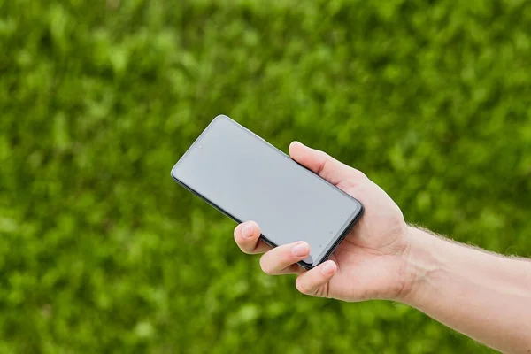 Een Zwarte Smartphone Een Mensenhand Met Wazige Kruiden Aan Horizon — Stockfoto