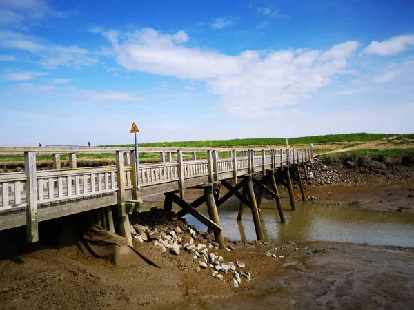 曇った空に向かって川を渡る木の橋 — ストック写真