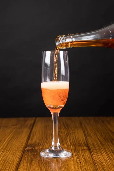 ボトルからグラスに注ぐバラのシャンパンの垂直ショット — ストック写真