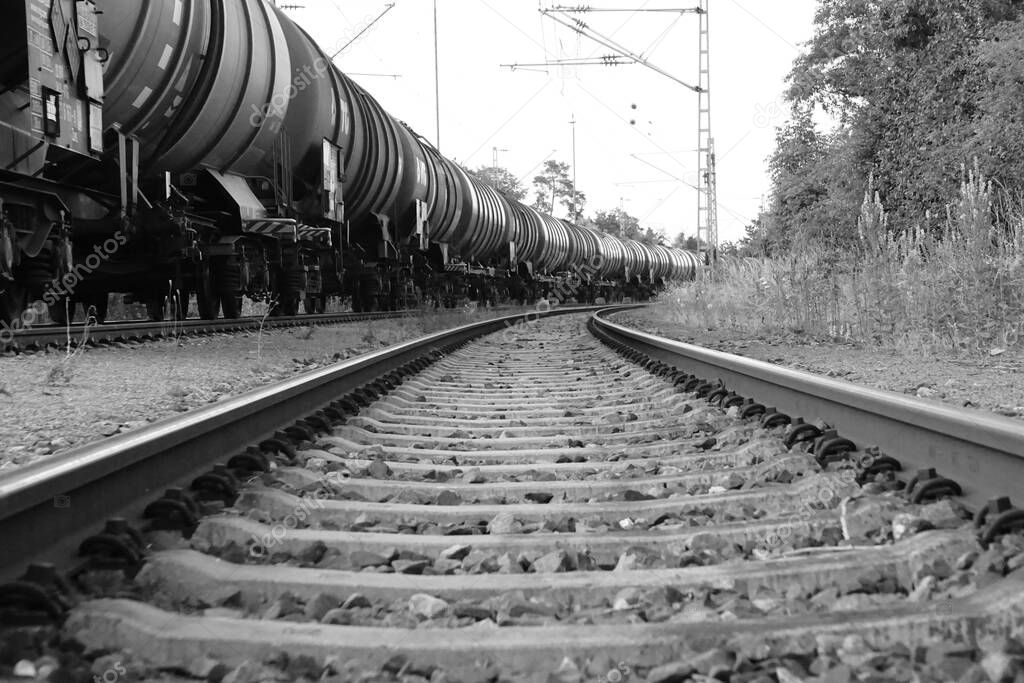 The grayscale view of the cargo train with oil tanker cars