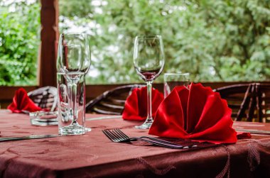 Lokantada gümüş takımlar, bardaklar ve peçetelerle dolu bir masa.