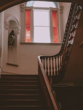 Güzel, ahşap bir merdiven, vitraylı bir pencere ve boyu dikey bir çekim.
