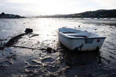 Çamurlu bir sahilde park etmiş bir teknenin yakın çekimi.