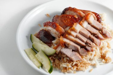 Beyaz arka planda pirinç ve salatalıkla servis edilen tavuk göğsüne yakın plan.