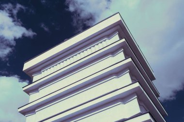 Bulutlu gökyüzünün altındaki modern bir gökdelenin alçak açılı görüntüsü.