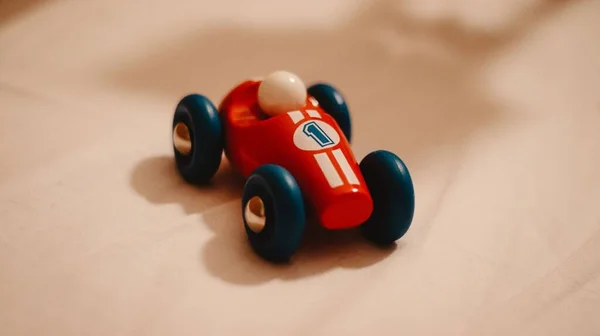 一辆上面有一号的玩具车一辆米色表面有蓝色轮子的红色轿车 — 图库照片