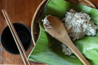 Büyük yeşil bir yaprak ve çubuk üzerinde küçük pirinçlerin yakın çekimi.