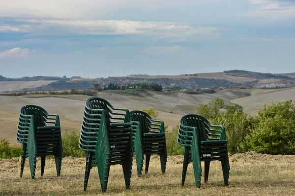 Některé Úhledně Naskládané Plastové Židle Poli Krásnou Krajinou Toskánska Pozadí — Stock fotografie